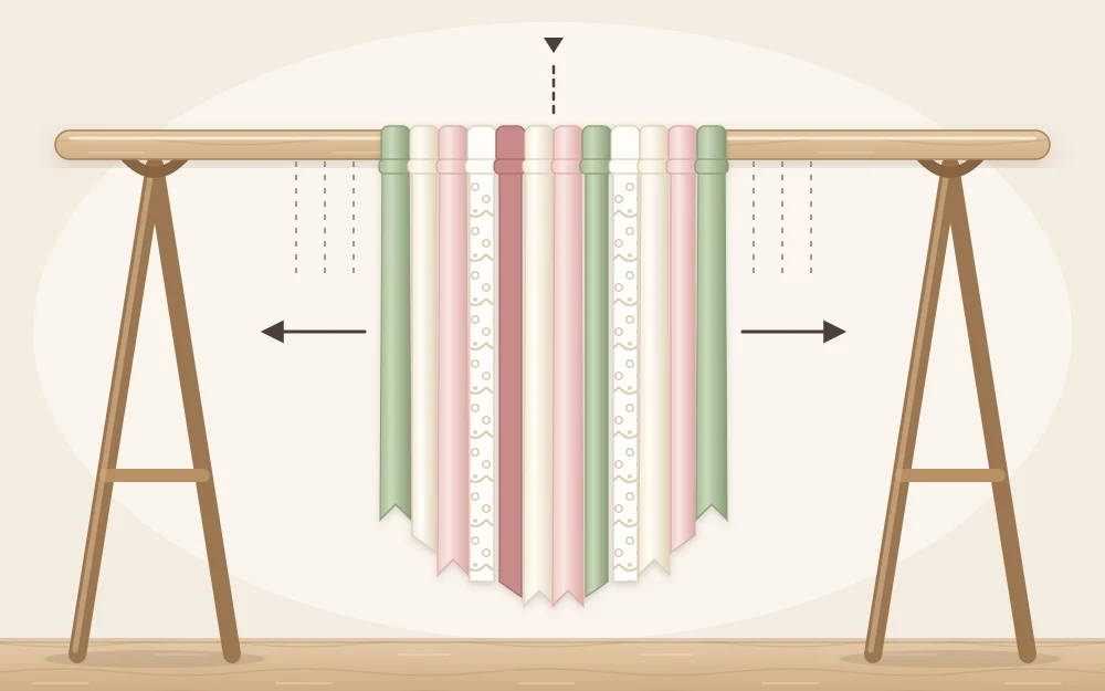 A wooden dowel lying across two supports with the first dozen ribbon and fabric strips knotted on from the center outward