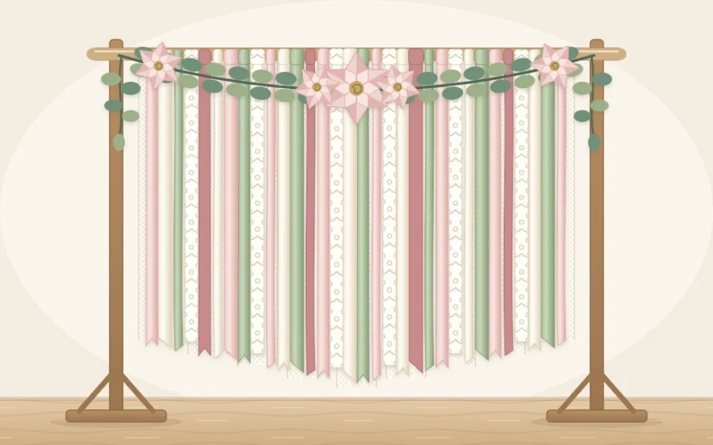 A curtain of long ribbons and sheer fabric strips in ivory, blush and sage hanging from a wooden pole on a stand, with a greenery swag on top