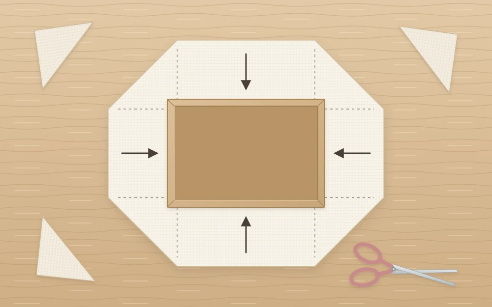 A box base placed on a piece of fabric with the fabric corners cut away diagonally, ready to be wrapped up the sides