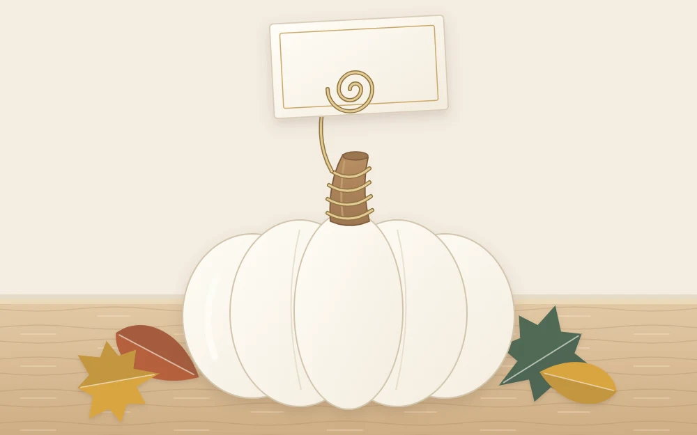 A small ivory pumpkin with a spiral of wire wound around its stem holding a small blank card upright