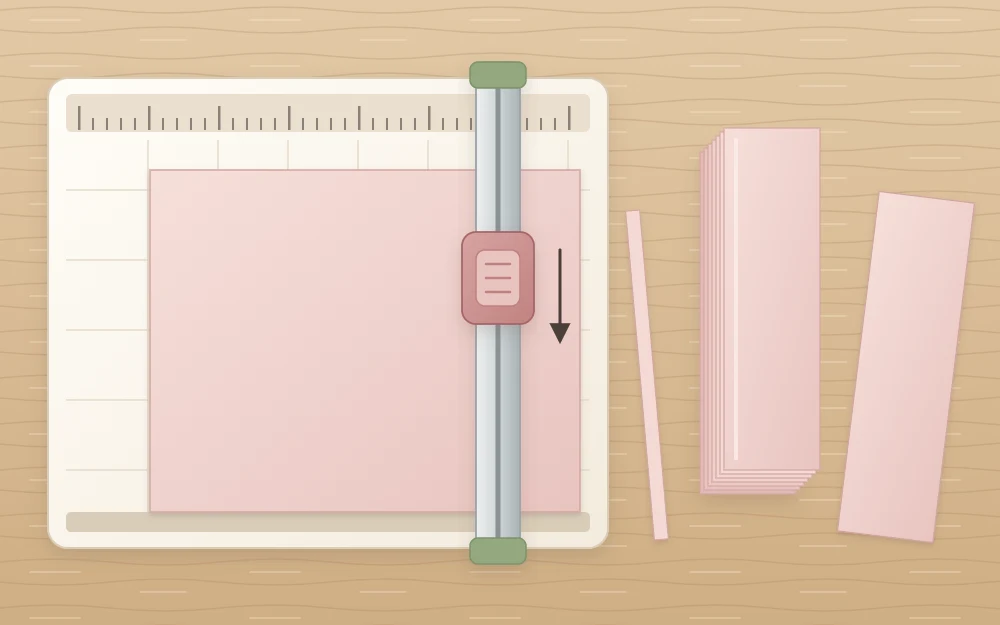 A paper trimmer with a cardstock sheet under its cutting arm beside a neat stack of identical strips