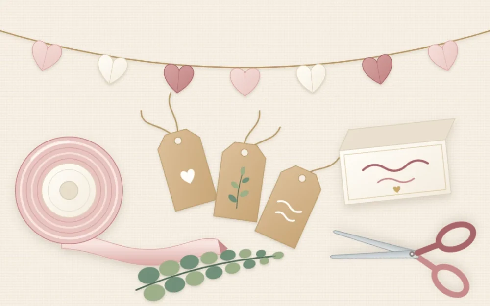 Flat lay of blush satin ribbon, kraft paper tags with twine, a folded tent place card, scissors, eucalyptus and a small paper heart garland