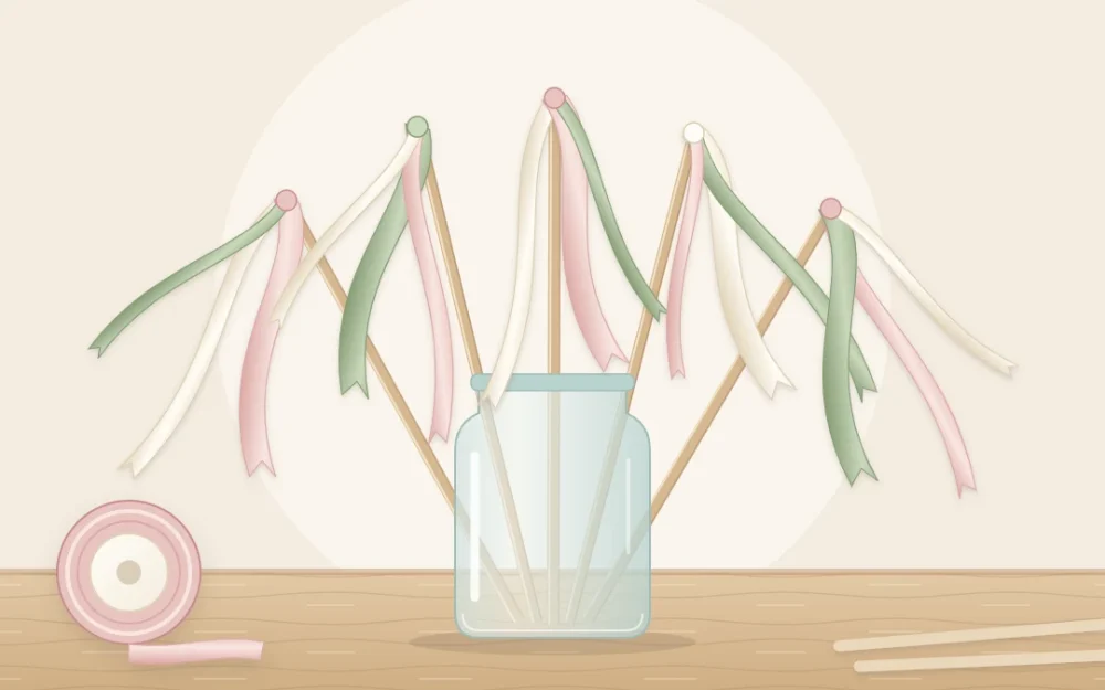 Five ribbon wands standing in a clear glass jar, thin wooden sticks with long flowing ribbons in blush, ivory and sage